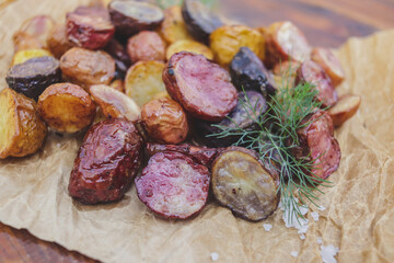 appetizing multi-colored young potatoes in the oven on parchment with salt and dill crust plan selective focus
