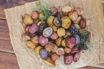 appetizing multi-colored young potatoes in the oven on parchment with salt and dill crust plan selective focus
