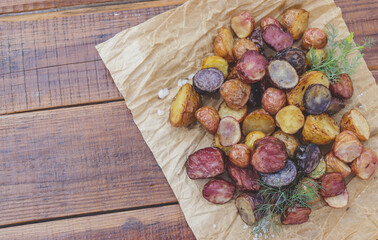 appetizing multi-colored young potatoes in the oven on parchment with salt and dill crust plan selective focus