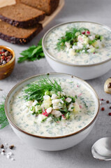 Cold Okroshka Soup with Eggs, Vegetables, Meat, Herbs and Kefir on a Bright Background, Summer Soup