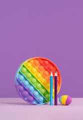 Colored pop it pad with eraser pencils on lilac purple background with rocket. stationery with copy space for back to school or education and craft concept. Bright minimal. Success achievement ideas