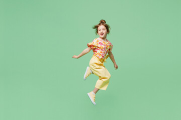 Full body sideways happy little child kid girl 6-7 years old wear casual clothes jump high raise up hands isolated on plain pastel green background studio. Mother's Day love family lifestyle concept.