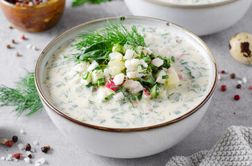 Cold Okroshka Soup with Eggs, Vegetables, Meat, Herbs and Kefir on a Bright Background, Summer Soup