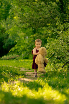 radiant photo of a toddler in a park, bearing a cuddly oversized teddy bear, experiencing her first adventures. adventures, and early-life experiences.