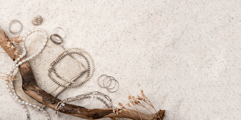 Beautiful Silver and Pearl Jewelry on white stones and sand. Various jewelry - bracelets, necklaces and rings. Banner with place for text.