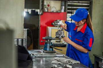 A female diesel engine mechanic in a blue uniform is working at the garage. Inspect and maintain the fuel pressure booster pump system and common rail injectors.