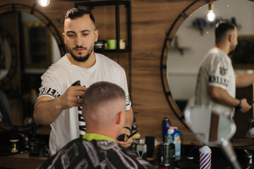 Fototapeta na wymiar Handsome man on a haircut in the barber sits on a chair.
