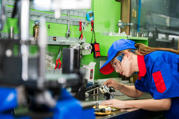 A female diesel engine mechanic in a blue uniform is working at the garage. Inspect and maintain the fuel pressure booster pump system and common rail injectors.