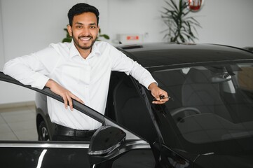 A young Indian man chooses a new car at a car dealership