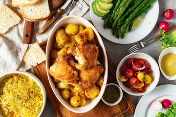 Home dinner table with set of various food from baked new potatoes with chicken thighs, vegetables...