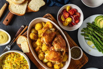 Home dinner table with baked new potatoes with chicken thighs, vegetables and salads top view, tasty and healthy food