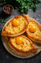 Ajarian Khachapuri, filled with cheese and topped with egg yolk, traditional Georgian Khachapuri on Dark Background