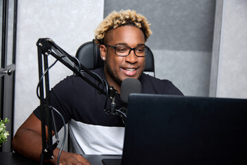 Radio DJ with glasses leads a popular program for listeners. Cheerful black podcaster at the...