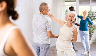 Group of positive adults doing Tango poses in training room during workout session