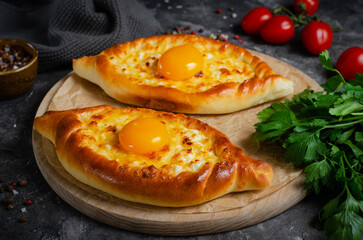 Ajarian Khachapuri, filled with cheese and topped with egg yolk, traditional Georgian Khachapuri on Dark Background