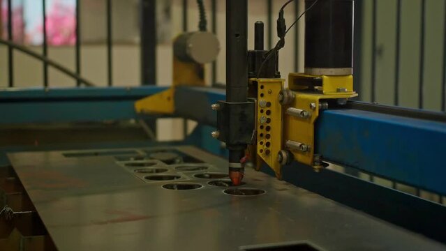 A laser cutting machine cuts a design in metal creating sparks.