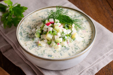 Cold Okroshka Soup with Eggs, Vegetables, Meat, Herbs and Kefir on a Wooden Background, Summer Soup