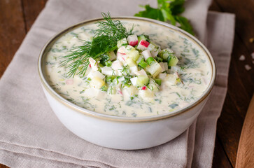 Cold Okroshka Soup with Eggs, Vegetables, Meat, Herbs and Kefir on a Wooden Background, Summer Soup