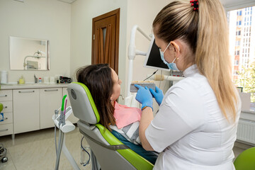 Stomatologist hands holding tooth samples for bleaching treatment female patient