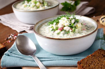 Cold Okroshka Soup with Eggs, Vegetables, Meat, Herbs and Kefir on a Wooden Background, Summer Soup
