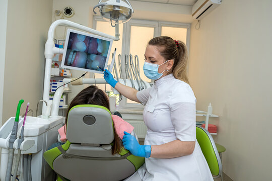 Female doctor use intro oral dental camera and watch on the monitor live picture of teeth her patient
