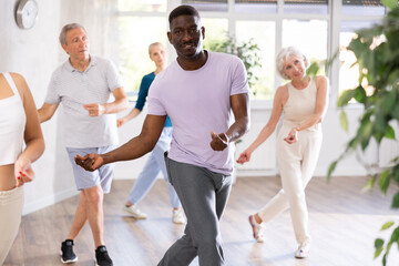 Group of multinational sports aged people rehearsing modern dance in dance hall