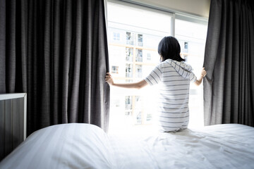 Asian young woman opening curtain and window for hygienic,sunlight to enter her bedroom and air...