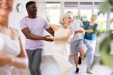Fototapeta premium African American man is enjoying his hobby of dancing salsa with his elderly partner at fitness class, relishing in movement and activity. It great way for them to stay active and have fun together.