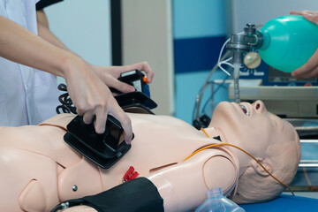 Hands of doctor physician performning cardioversion with defibrillator on a mannequin,advance cardiac life support course training.Healthcare Concept