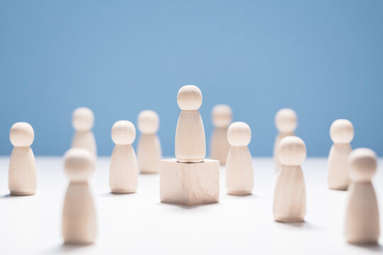 Leadership, wooden business team with one person on podium standing out from the crowd