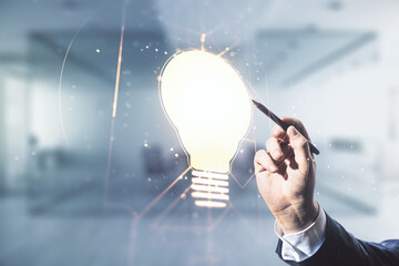 Double exposure of male hand with pen draws creative light bulb hologram on blurred office background, research and development concept