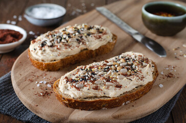 Hummus Toast with Rustic Bread, Vegetarian Snack or Breakfast on Wooden Background