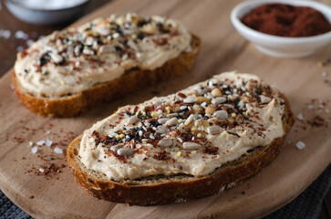 Hummus Toast with Rustic Bread, Vegetarian Snack or Breakfast on Wooden Background