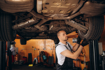 Fototapeta na wymiar Auto mechanic repairman using a socket wrench working auto suspension repair in the garage, change spare part, check the mileage of the car, checking and maintenance service concept