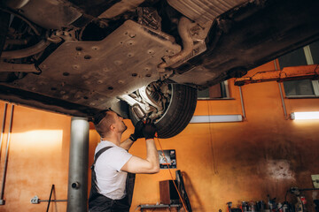 Auto mechanic repairman using a socket wrench working auto suspension repair in the garage, change...