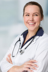 Female family doctor in doctor's overall with stethoscope in front of a clinic room
