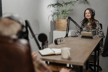 Two announcers are broadcasting jointly at the radio station. A man and a woman sit at a table...