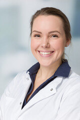 Smiling female family doctor in doctor's overall in front of a clinic room