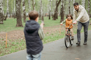 Father supporting son riding bicycle at park