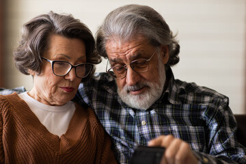 An elderly couple get acquainted with the modern capabilities of mobile phones. Seniors and modern electronics.