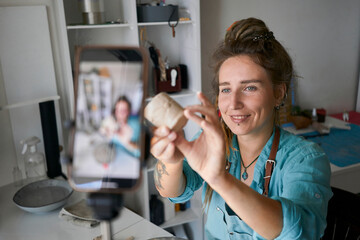 Smiling influencer recording video of clay cup at workshop