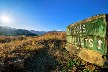 Shebas Breasts text carved on rocks with mountains and blue sky in background