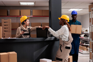 Delivery service assistants team scanning black box at desk for shipment. Warehouse operator giving...