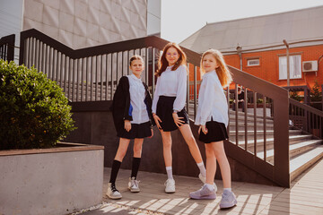 Smiling school girls standing near stairs on school yard