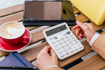Hand of businesswoman using calculator with coffee on table