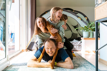 Cheerful family enjoying with VIzsla dog at home