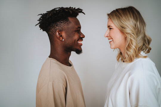 Smiling young woman embracing boyfriend against gray background