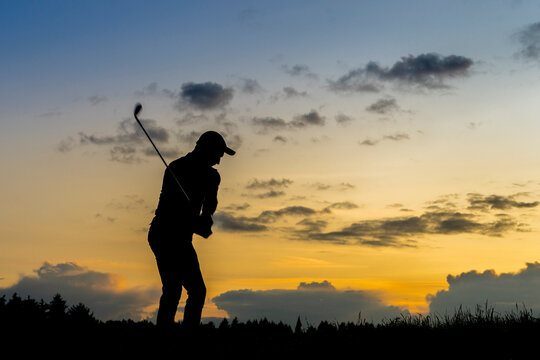 Silhouette of man playing golf at dusk