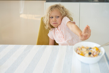 Girl refusing breakfast at table