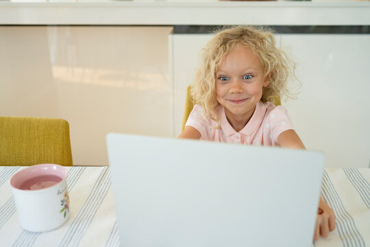 Smiling girl making face in front of laptop at home